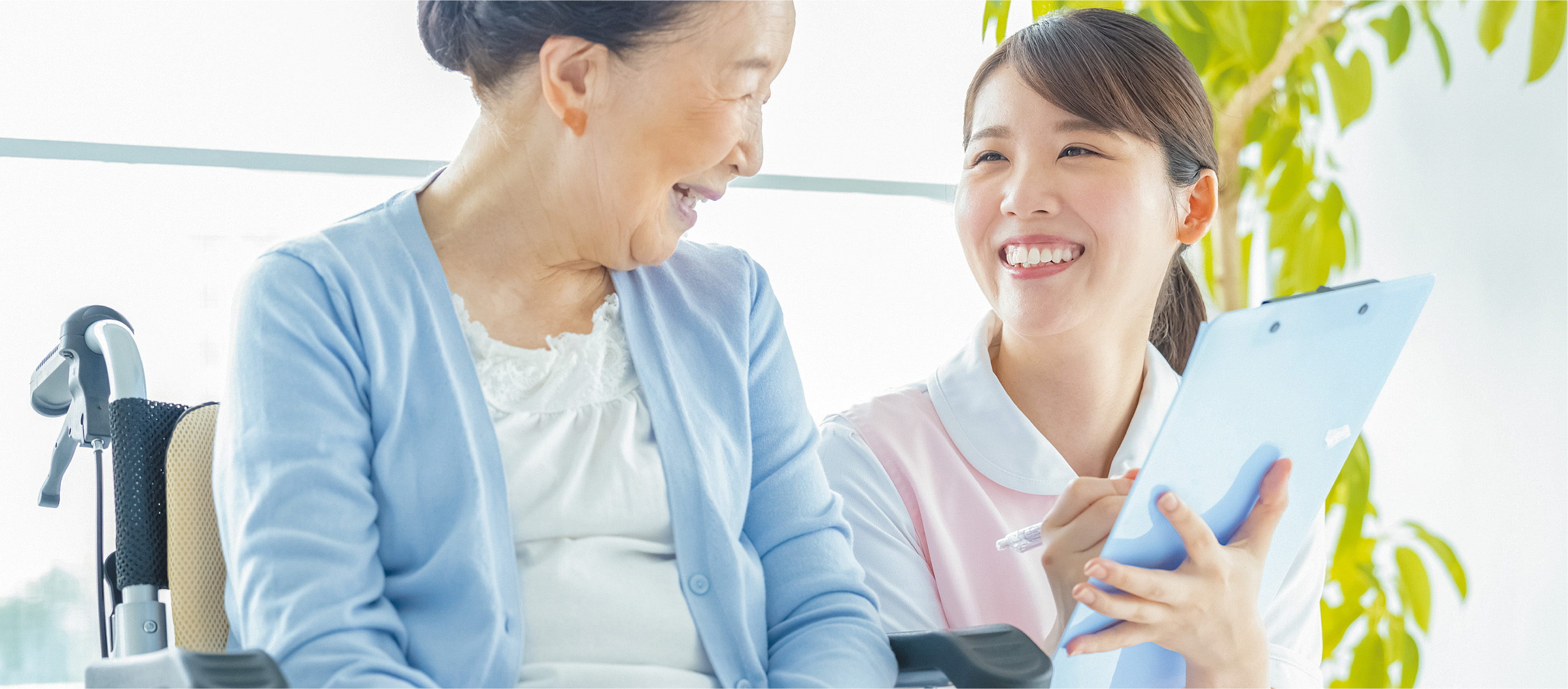 車椅子の女性と笑顔で話す介護士