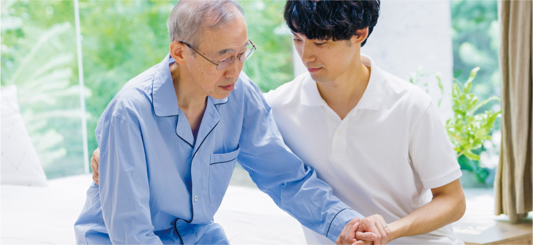 立とうとする男性をサポートする介護士
