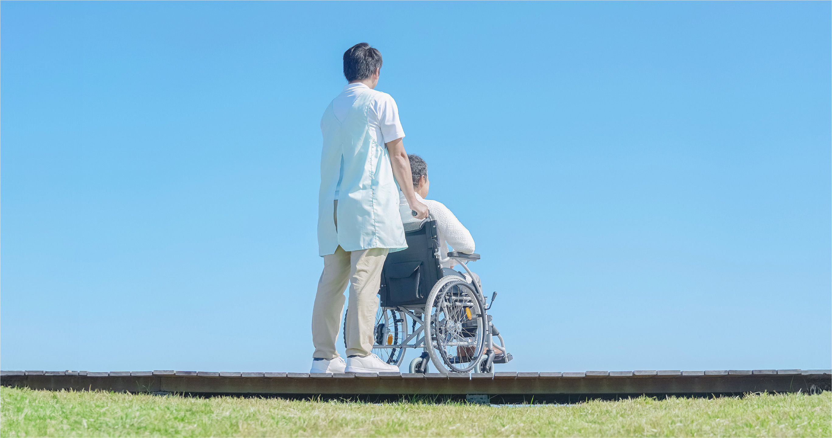 こちらに背を向ける看護師と車椅子の男性